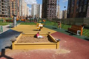Child playing in the sandbox in the playground in the courtyard of a house photo