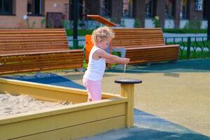 Child playing in the sandbox in the playground in the courtyard of a house photo