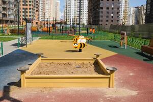 Child playing in the sandbox in the playground in the courtyard of a house photo