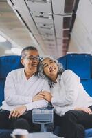 A mature couple enjoys a plane ride sitting near the window. They looked out into the sky. Immerse yourself in the scenery and excitement of the journey. To create precious memories together photo