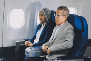 A mature couple enjoys a plane ride sitting near the window. They looked out into the sky. Immerse yourself in the scenery and excitement of the journey. To create precious memories together photo