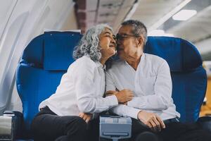 A mature couple enjoys a plane ride sitting near the window. They looked out into the sky. Immerse yourself in the scenery and excitement of the journey. To create precious memories together photo