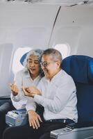 A mature couple enjoys a plane ride sitting near the window. They looked out into the sky. Immerse yourself in the scenery and excitement of the journey. To create precious memories together photo