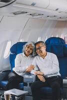 A mature couple enjoys a plane ride sitting near the window. They looked out into the sky. Immerse yourself in the scenery and excitement of the journey. To create precious memories together photo