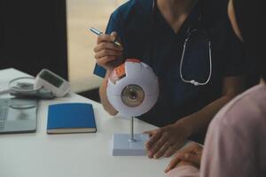 Ophthalmologist doctor in clinic, part of eye model on desk, oculus sample photo