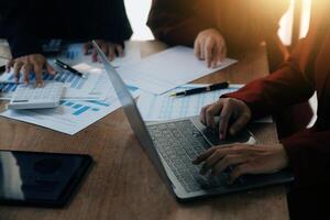 Group of confident business people point to graphs and charts to analyze market data, balance sheet, account, net profit to plan new sales strategies to increase production capacity. photo