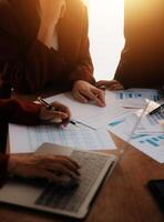 Group of confident business people point to graphs and charts to analyze market data, balance sheet, account, net profit to plan new sales strategies to increase production capacity. photo