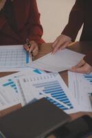Group of confident business people point to graphs and charts to analyze market data, balance sheet, account, net profit to plan new sales strategies to increase production capacity. photo