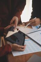 Group of confident business people point to graphs and charts to analyze market data, balance sheet, account, net profit to plan new sales strategies to increase production capacity. photo
