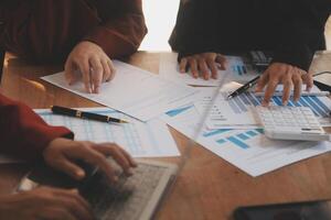 Group of confident business people point to graphs and charts to analyze market data, balance sheet, account, net profit to plan new sales strategies to increase production capacity. photo