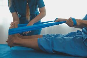 Professional orthopedist examining the little patient's leg in the clinic. Patient at the physiotherapy doing physical exercises with his therapist photo