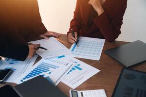 Group of confident business people point to graphs and charts to analyze market data, balance sheet, account, net profit to plan new sales strategies to increase production capacity. photo