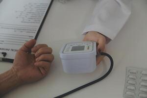 Doctor using sphygmomanometer with stethoscope checking blood pressure to a patient in the hospital. photo