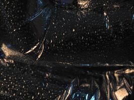 Water drops on silver foil surface in dark for abstract background. photo