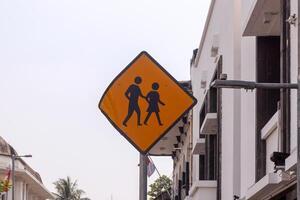 A yellow pedestrian sign with sky and buildings in the background photo
