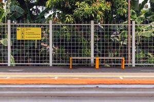 Jakarta, Indonesia, 2024 - Waiting area for train passengers at a station in Jakarta with a bench and directional signboard photo