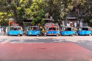 Jakarta, Indonesia, 2024 - Row of bajaj parked on the side of the road in Jakarta. Waiting for passenger. Blue Bajaj is a three-wheeled public transportation. photo