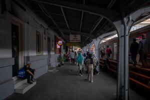 Jakarta, Indonesia, 2024 - The atmosphere of the platform at Jakarta Kota Train Station with crowds of people. A stopped train and an old platform building. photo