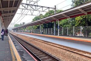 Jakarta, Indonesia, 2024 - Passengers waiting for the train to arrive at the station. View of a commuter line train platform in Jakarta. photo