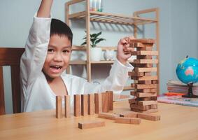 Cheerful Asian boy playing with wooden building blocks Jenga, Having fun and learning creativity, smart kid concept. photo