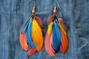 Colorful feather earrings displayed on a textured fabric background, close up view photo