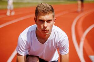 Young male athlete preparing for a race on a running track photo