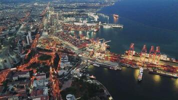 Drone films seaport at night highlighting illuminated port facilities Port cranes loading and unloading cargo scene captures bustling port activities under night sky with cranes operating efficiently video