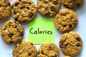 chocolate chip cookies on withe background with a Calorie text written on a sticky note photo