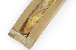 Freshly baked French baguette in a brown paper bag isolated on a white background.Loaf of white bread wrapped in eco-friendly sustainable brown paper bag. Copy space. With clipping path. photo