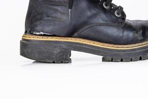 Closeup detail of one black worn ankle leather combat boot with thick, sturdy sole and laces. Single vintage military style shoe. Studio light. Isolated on white background. Empty copy space. photo