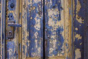 Vintage rustic door with a metallic lock and door handle. Detailed old wooden texture with chipped paint and a worn-out surface. Antique doorknob design. Backdrop for creative projects. Copy space photo
