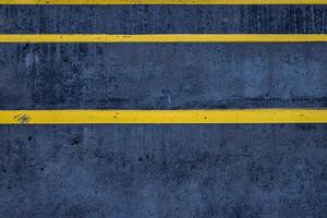 Closeup of a textured asphalt road with weathered yellow stripes on a rough gray pavement, great for use in street photography, urban design, or traffic-related visuals. Copy space photo