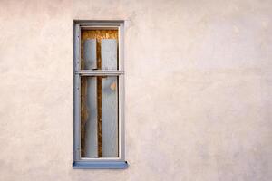 Minimalistic exterior wall with an old boarded up sealed closed window in a rustic frame. Perfect for urban decay themes and architectural design elements. Copy space photo