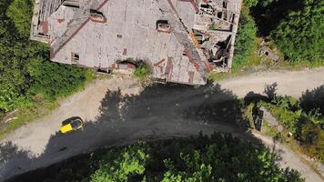 Drone view of an old abandoned high-rise building past which a yellow car passes video