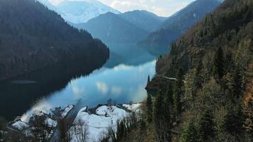 Clear blue mountain lake with reflection of clouds on the water. Drone view video