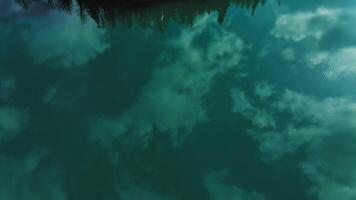 Clear blue mountain lake with reflection of white clouds on the water Drone view video