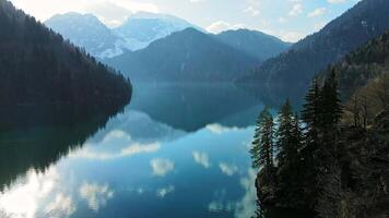 Clear blue mountain lake with reflection of clouds on the water. Drone view video