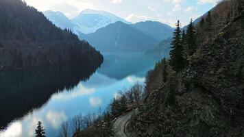 Clear blue mountain lake with reflection of clouds on the water. Drone view video