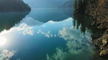 Clear blue mountain lake with reflection of clouds on the water. Drone view video