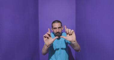 Man doing frame using hands and fingers, isolated over purple background video