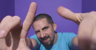 Young man doing frame using hands and fingers, isolated over purple background video