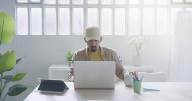 à moda barbudo trabalhador autonomo trabalhando remotamente a partir de lar. milenar trabalhando em computador escrivaninha video