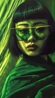 Captivating Asian Female Model in Vivid Green Studio Portrait with Glasses and Dark Mood photo