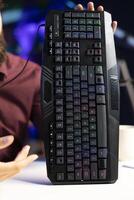 Close up shot of gaming keyboard presented by influencer filming review in personal studio. RGB lit computer peripheral showcased by content creator for viewers of technology channel photo