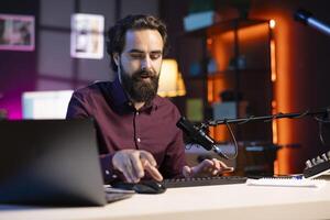 Tech guru filming tutorial for online channel in studio, presenting helpful keyboard shortcuts. Content creator pressing keys on computer peripheral device, filming for audience photo