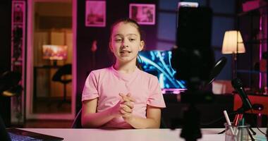 Close up shot on smartphone attached to tripod in living room used as professional studio for recording vlogs. Focus on phone camera capturing footage of kid in blurry background discussing topics photo
