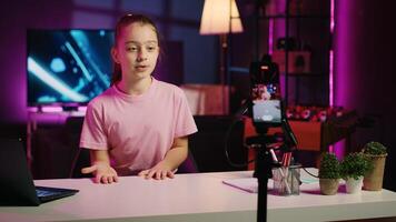 Child filming with phone on tripod stabilizer for her newly opened online channel, talking with viewers. Kid telling audience her name and what topics she wishes to explore in future clips photo