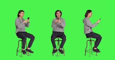 Adult typing text messages on phone while sitting on chair, browsing social media app for messaging on smartphone. Young trendy person using device to communicate with people. photo
