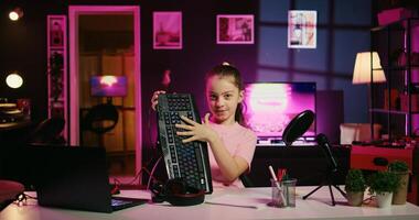 Cute child hosting internet show promotes wireless keyboard and mouse received from sponsoring brand. Little girl does influencer marketing, urging fans to purchase computer peripherals photo