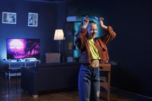 Child performing trending dance routine in living room, surrounded by computer screens displaying 3D animations. Kid dancing inside neon lit home studio, creating content for online fans photo